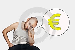 Bald sad man sits and thinks about money and a small salary in Euro
