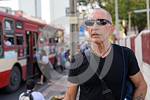 Bald senior tourist man thinking while wearing sunglasses at the