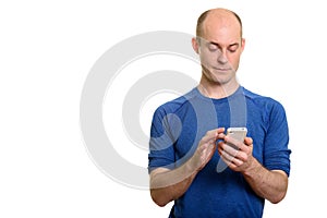 Bald serious Caucasian man using mobile phone