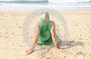 A bald and unusual young man, a freak, with a shiny bald head and round wooden glasses on the background of the beach and the sea