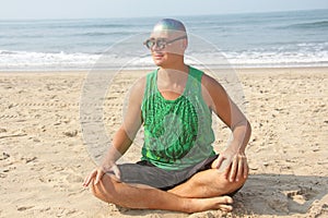 A bald and unusual young man, a freak, with a shiny bald head and round wooden glasses on the background of the beach and the sea