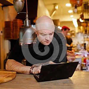 Bald young man looking at laptop