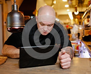 Bald young man looking at laptop