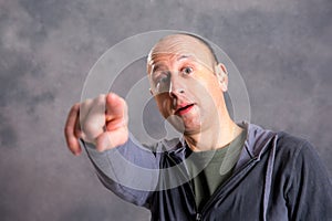 Baldheaded man pointing in to the camera photo