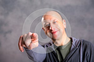 Baldheaded man pointing in to the camera photo