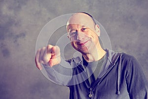 Baldheaded man pointing in to the camera photo