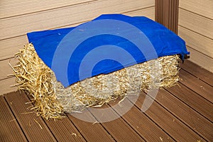 Bale of hay on floor near wooden wall