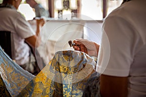 Bali - Indonesia - 10.22.2015: Balinese male and female artists applying wax on batik cloth in a touristic workshop