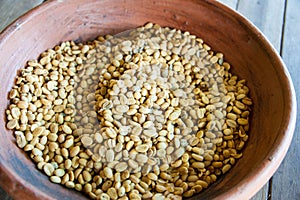 Bali, Indonesia.: Kopi Luwak coffee berries in red terracotta bowl on wooden trestle table photo