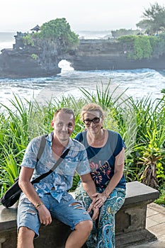 BALI, INDONESIA - MAY 4, 2017: Woman and her son on a background of Pura Tanah lot temple, Bali island, Indonesia.