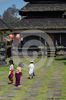 26.12.2018, Bali, Indonesia. Small Balinese children walk to the temple on a mossy path. Rear view