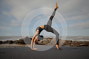 Bali yoga. Slim Asian woman practicing Eka Pada Chakrasana, One Legged Wheel Pose. Upward facing bow pose is a deep backbend.