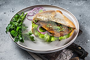 Balik Ekmek Turkish fish sandwich with grilled mackerel fillet in a bun. Gray background. Top view