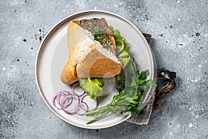 Balik Ekmek Turkish fish sandwich with grilled mackerel fillet in a bun. Gray background. Top view