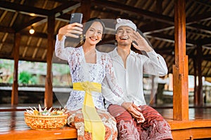 balines couple make a video call during holy day of galungan