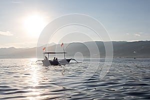 Balinese boats with tourists during sunset colors over the calm sea in Lovina