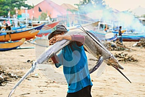 fishmonger carry Marlin fish at the morning market