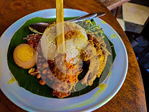 Balinese mixed rice dish with chicken skewer, grilled chicken, vegetables, and egg.