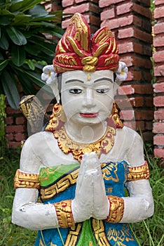 Balinese sculpture with red flower in garden in Lovina, Bali. In