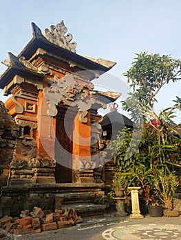 Balinese traditional building in the form of an entrance made of stone with a background of blue sky and green