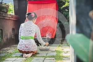Balinese woman doing ritual offering canang sari and praying at