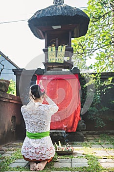 Balinese woman praying at temple on small shrines in houses