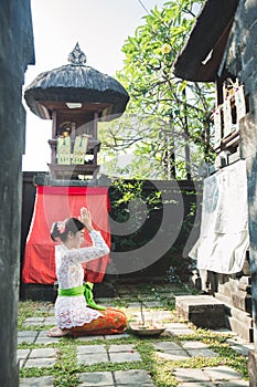 Balinese woman praying at temple on small shrines in houses