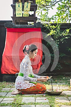 Balinese woman praying at temple on small shrines in houses