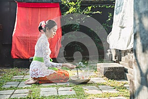 Balinese woman praying at temple on small shrines in houses