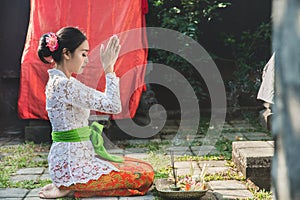 Balinese woman praying at temple on small shrines in houses