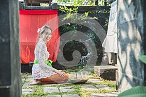 Balinese woman smiling after praying at temple on small shrines