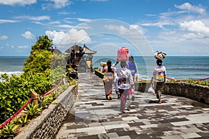 Balinese women carrying baskets with offerings to a temple at Pura Tanah Lot, Bali Island, Indonesia