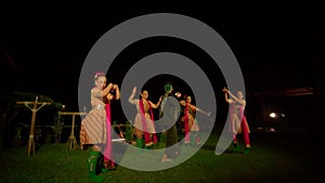 Balinese women celebrate the ritual ceremony with dancing while a man wasting money to the sky between the dancer on the stage