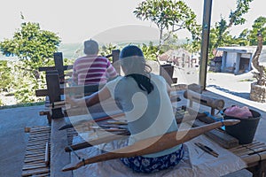 Balinese women work in an open weaving workshop on looms. Processing of hand-dyed cotton fibers. Workers work in a loom house.