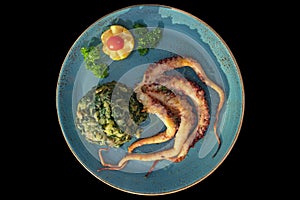 Balkan cuisine. Dish with grilled octopus isolated on black background. Flat lay