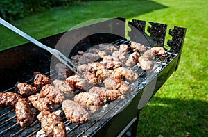 Balkan meatballs called cevapi on barbecue with BBQ fork photo