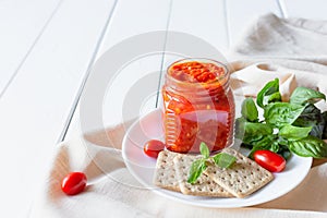 Balkan traditional dish ajvar, lutenitza, pingjur, with bread on a plate on white wooden table. Serbian traditional food