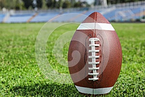 Ball for American football on fresh green field grass