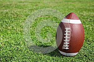 Ball for American football on fresh green field grass.