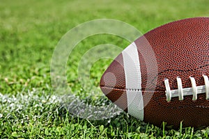 Ball for American football on fresh green field grass