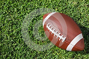 Ball for American football on fresh green field grass