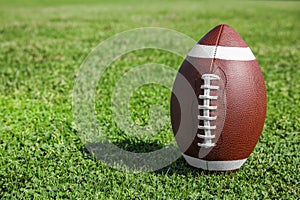 Ball for American football on fresh green field grass