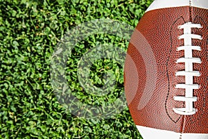 Ball for American football on fresh green field grass, top view