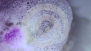 A ball of bath salt dissolving in water alongside an essential oils for better sleep | Relaxing fizzy bath bomb