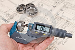 Ball bearings measurement. Micrometer screw gauge in human hand photo