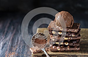 A ball of chocolate ice cream on a chocolate bar with nuts.