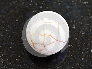 Ball from cracked Cacholong gemstone on dark