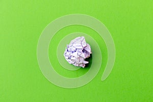 A ball of crumpled office paper on a green background.