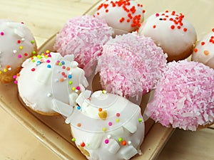 Ball donuts scatter over of colorful sugar.