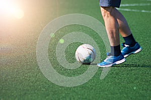 The ball and feet of a soccer player on the green surface of the stadium. game situation. Sunshine. Selective focus